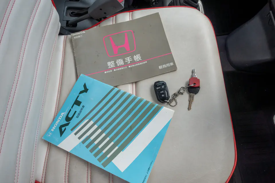 Honda Acty maintenance record book and keys resting on the seat