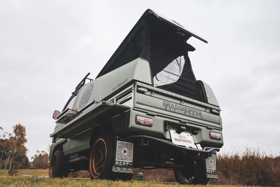 Kei Truck camper with its pop-up roof tent open on the grass