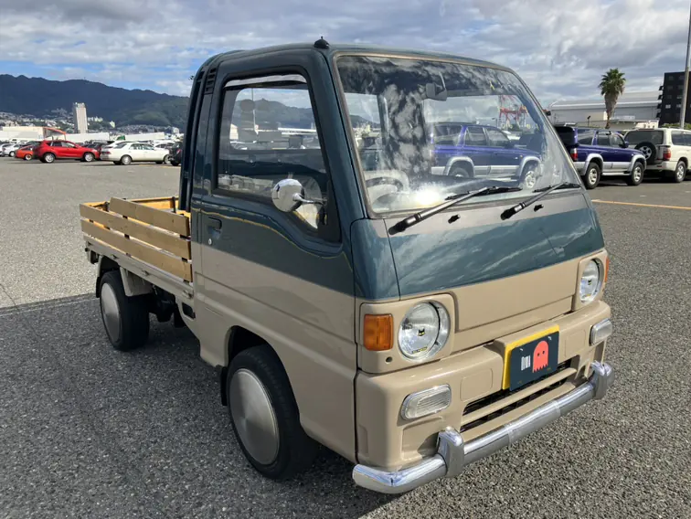 Two-tone Subaru Sambar Kei Truck with round headlights, chrome bumpers and wooden bed rails